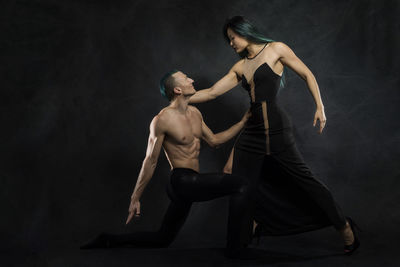 Young man and woman dancing against gray background