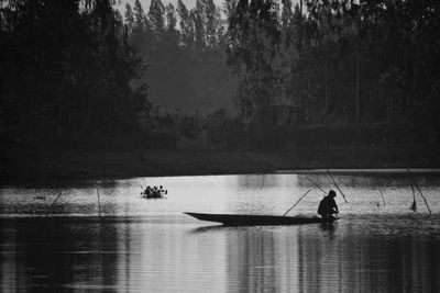 Silhouette man standing on boat in lake