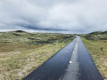 Road amidst field against sky