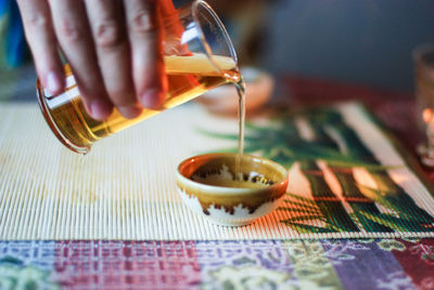 Close-up of hand pouring tea cup on table