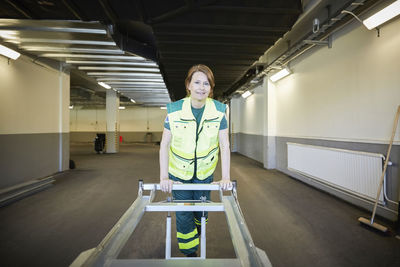 Portrait of female paramedic with stretcher in corridor at hospital