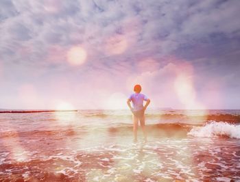 Boy stay in cold water at sea shore.  cold water waves washing hisd knees. abstract lighting flare.