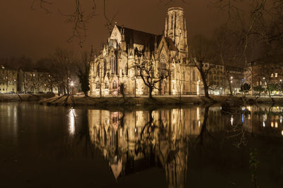 Reflection of trees in lake against sky in city