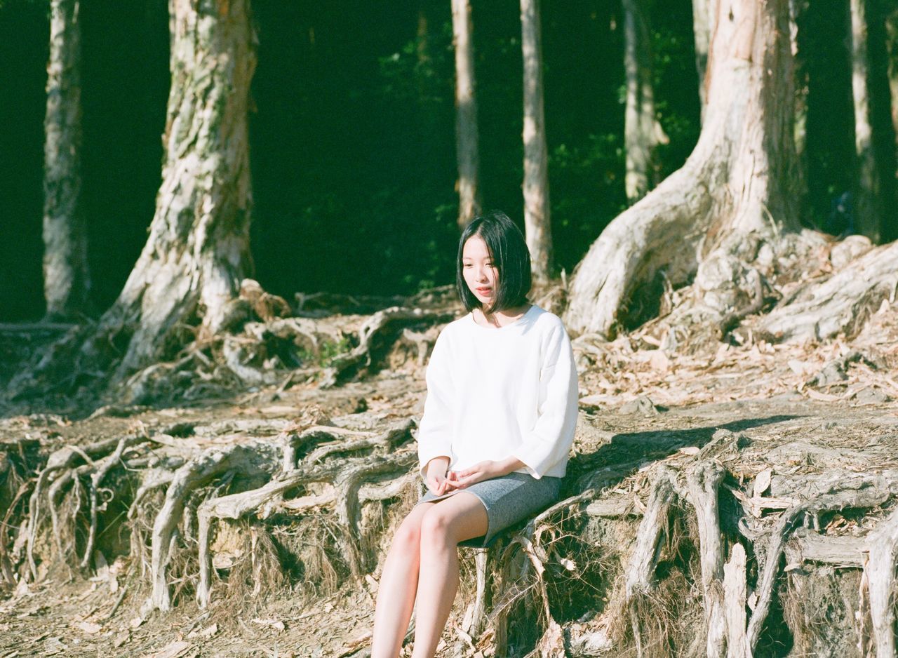 lifestyles, tree, casual clothing, tree trunk, leisure activity, young adult, standing, forest, three quarter length, tranquility, nature, person, full length, landscape, plant, growth, day, young women