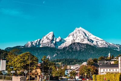 Houses by trees and mountains against blue sky