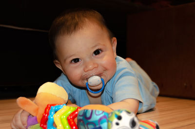 Portrait of cute boy with pacifier by toys