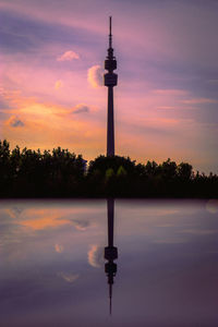 Silhouette tower by lake against sky during sunset