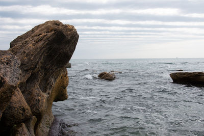 Rock formation by sea against sky