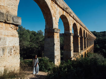 Man standing by arch bridge against sky
