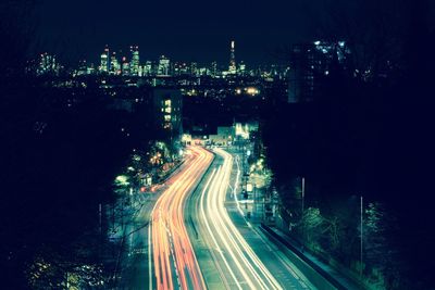 Light trails on city street against sky at night