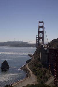 Suspension bridge over sea against clear sky