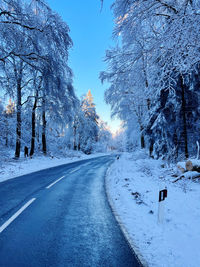 Road amidst snow covered trees against sky