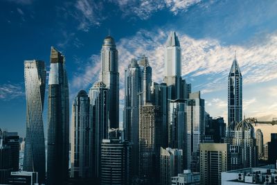 Modern buildings in city against cloudy sky