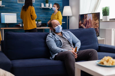 Rear view of people sitting on sofa at home