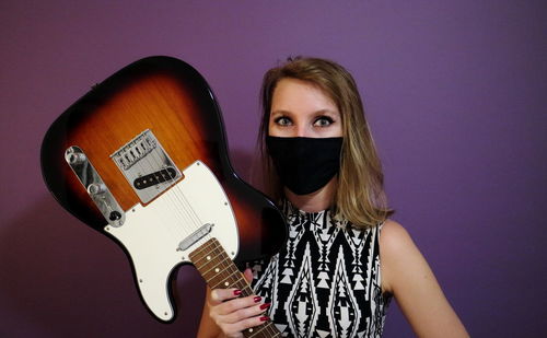 Portrait of young woman holding guitar