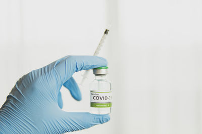Close-up of hand holding bottle against white background