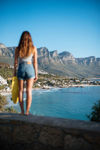 Rear view of woman looking at sea against mountains