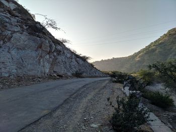 Road leading towards mountains against clear sky