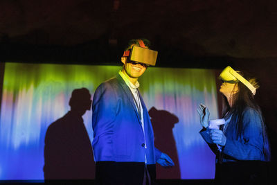 Happy businessman watching through futuristic glasses with female colleague in convention center