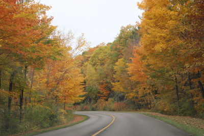 Road amidst trees against sky during autumn