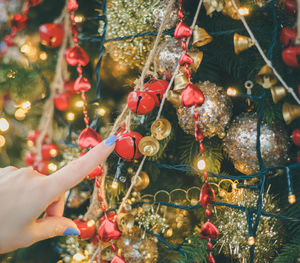 Cropped hand of woman touching christmas tree 