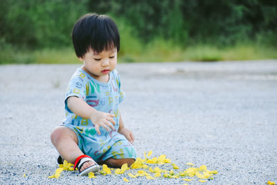 Full length of cute baby boy sitting on street