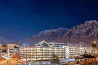 Illuminated buildings against sky at night during winter