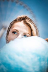 Portrait of young woman by cotton candy against ferris wheel