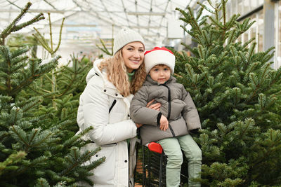 Mother and son buy a christmas tree at a market.