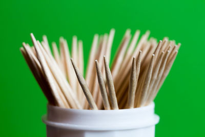 Close-up toothpicks in container against green background