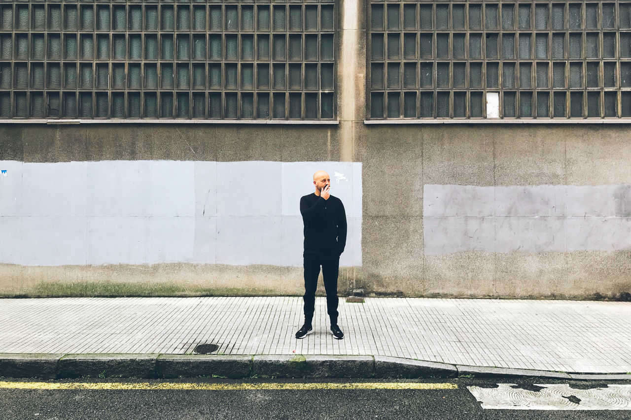 FULL LENGTH OF A MAN STANDING IN FRONT OF BUILDING