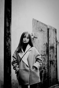 Portrait of young woman standing against wall