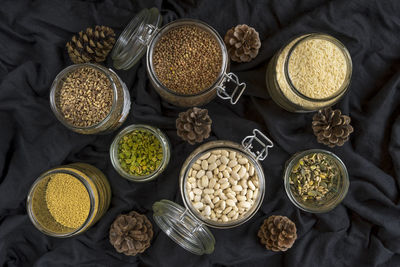 Directly above shot of various food in jars with pine cones on tablecloth