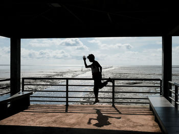 Rear view of man standing on pier