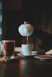 Cropped hand of woman pouring water in coffee