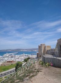 Buildings by sea against blue sky