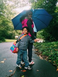 Portrait of mother and son with umbrella standing on road