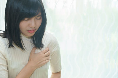 Woman suffering heartache against wall