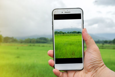 Midsection of person holding smart phone against sky