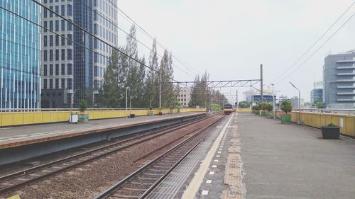 Railroad tracks in city against clear sky