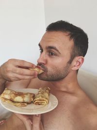 Close-up of shirtless man eating food