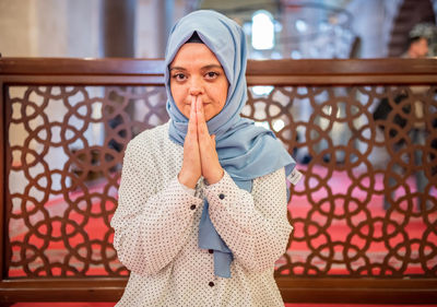 Portrait of woman praying while sitting in mosque