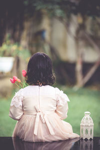 Rear view of woman standing by flowering plants