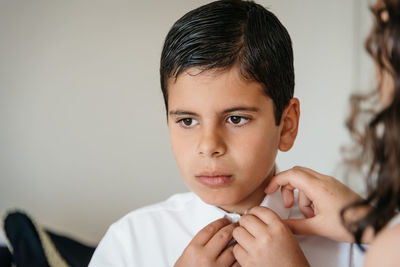 Cropped image of sister buttoning brother school uniform at home