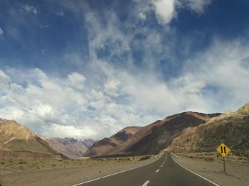 Road by mountains against sky