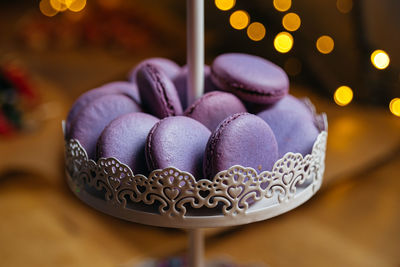 Lilac macaroons on a dessert stand. in the background, a bokeh effect from the yellow lights.