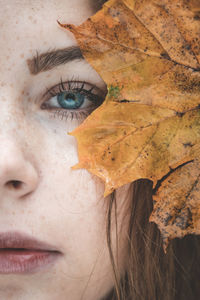 Close-up portrait of blue eyed woman with maple leaf