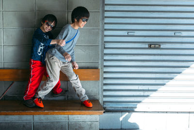 Siblings playing on bench against wall