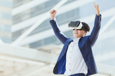 Businessman wearing virtual reality simulator against office building