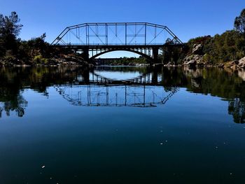 Arch bridge over lake against blue sky